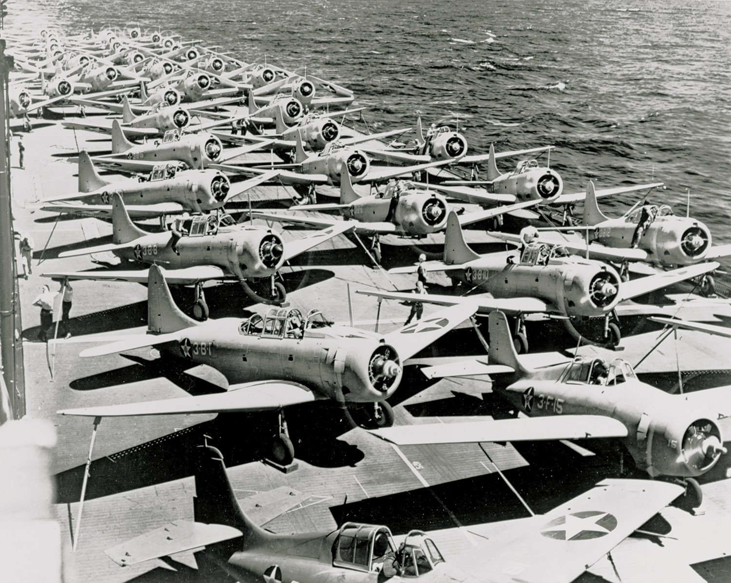 USS Saratoga flight deck circa fall 1941 with Grumman F4F-3 aircraft in the foreground and Douglas SBD-3 Dauntless and TBD-1 Devastator aircraft parked further back.